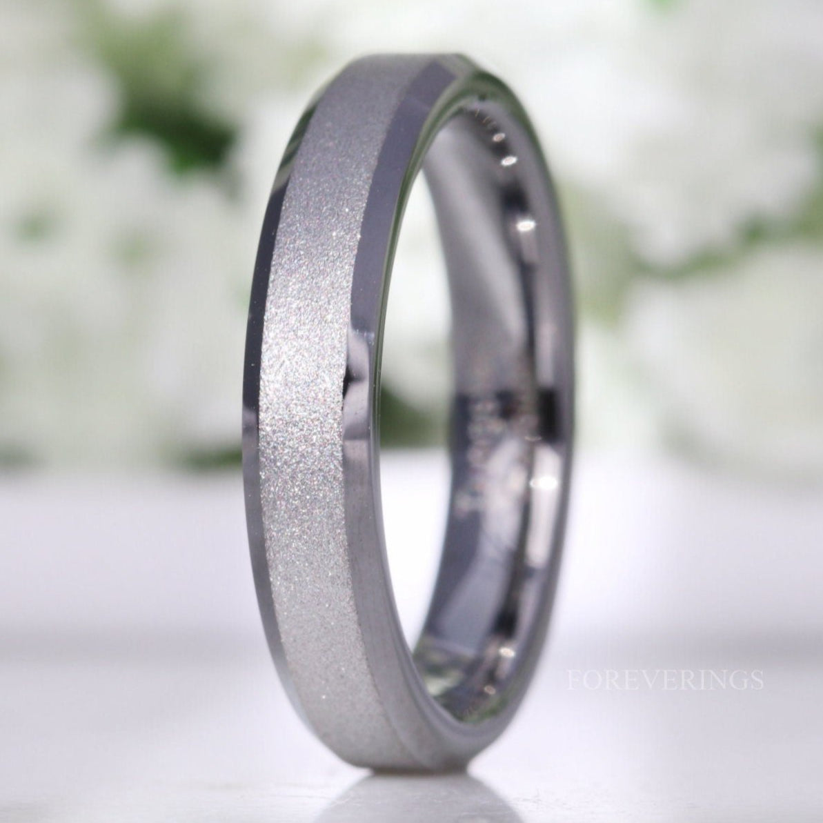 4mm silver sandblasted tungsten ring with beveled edges, standing on edge in a close crop