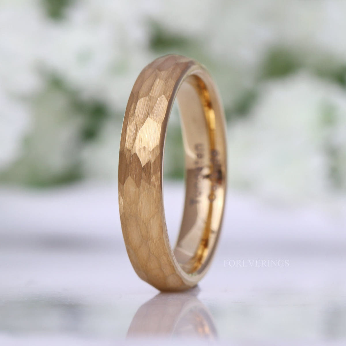 4mm hammered gold tungsten band standing at an angle, matte facets outside and polished gold inside