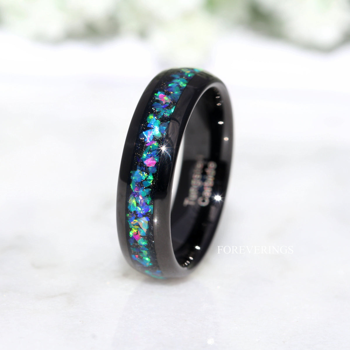 His 6mm black tungsten ring with galaxy opal inlay, angled from above on a white surface