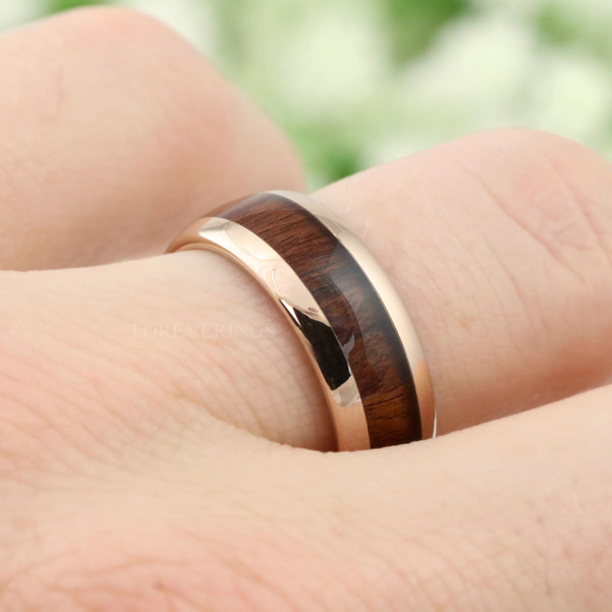 Koa wood and rose gold tungsten band on a hand, seen from the side