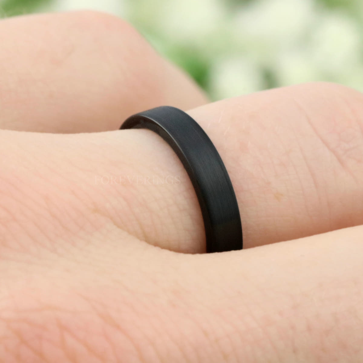 4mm matte black tungsten band on a finger, straight on close crop