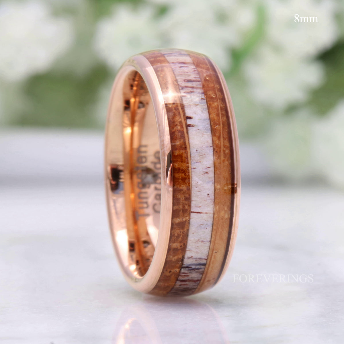 Men's 8mm rose gold tungsten band with whiskey barrel wood and antler inlay, standing angled