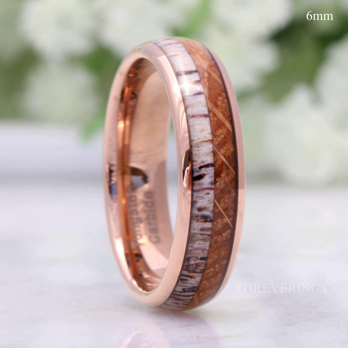 Men's 6mm rose gold tungsten band with whiskey barrel wood and antler inlay, standing on edge