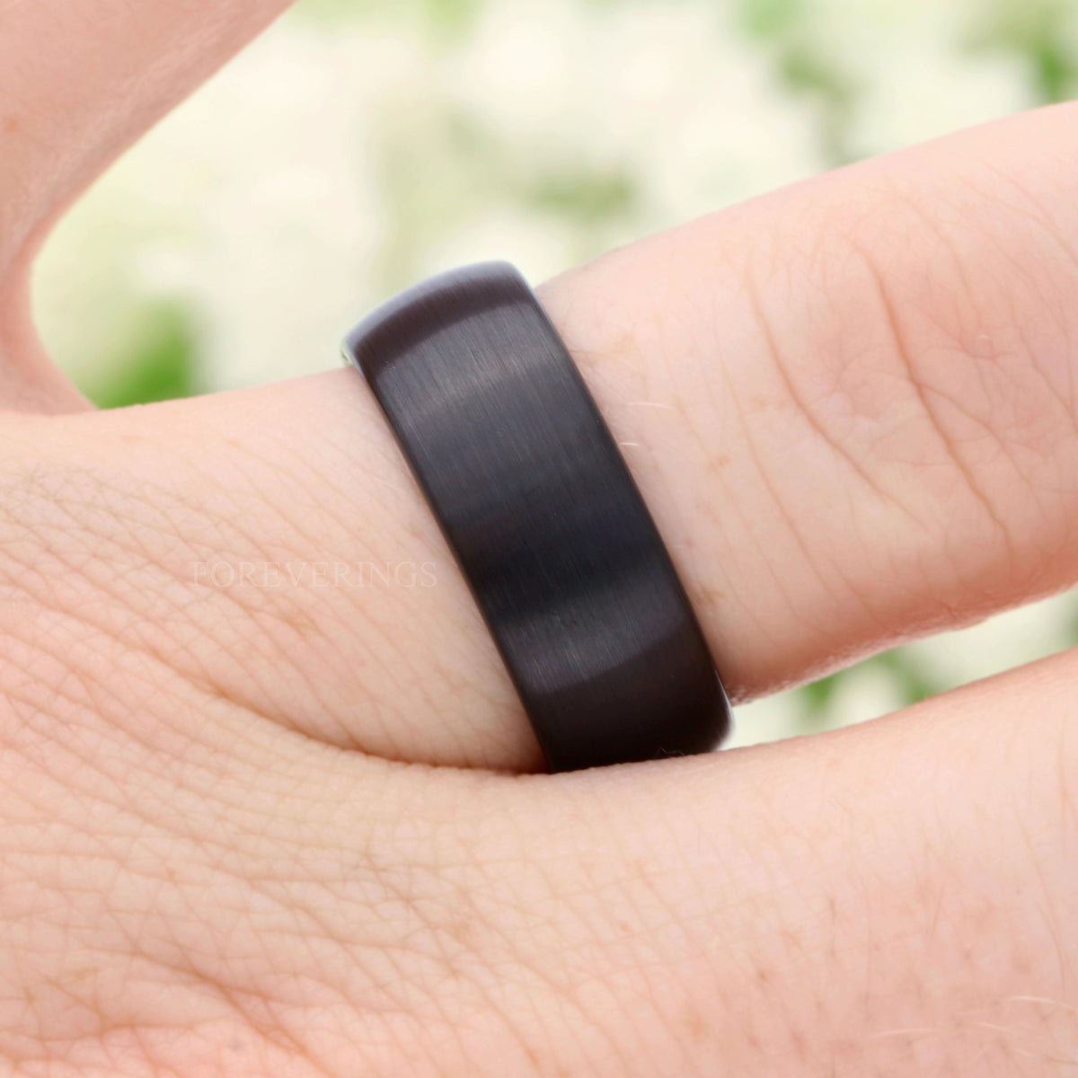 Men's 8mm brushed black tungsten wedding band worn on a finger