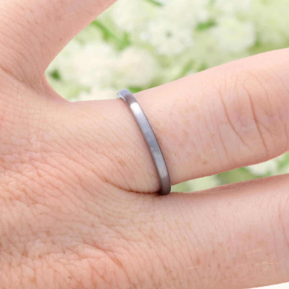 2mm thin brushed silver tungsten band worn on a finger, side view