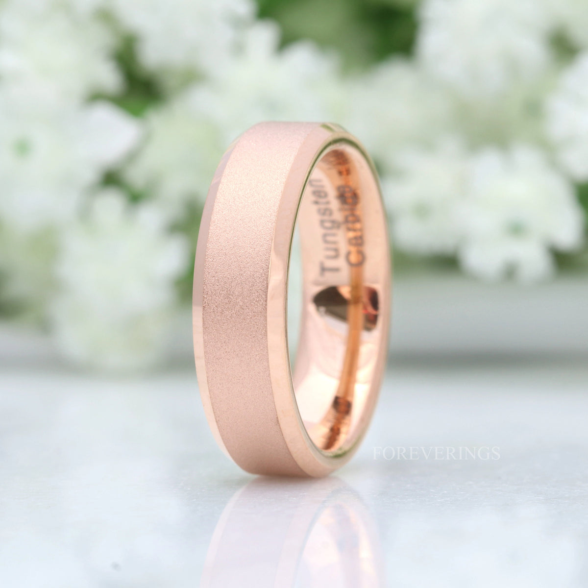 Sandblasted rose gold tungsten band with beveled edges, standing upright with interior visible
