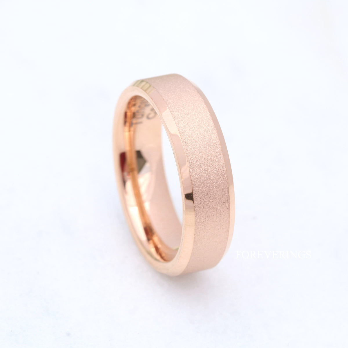 Sandblasted rose gold tungsten band angled from above on a white background