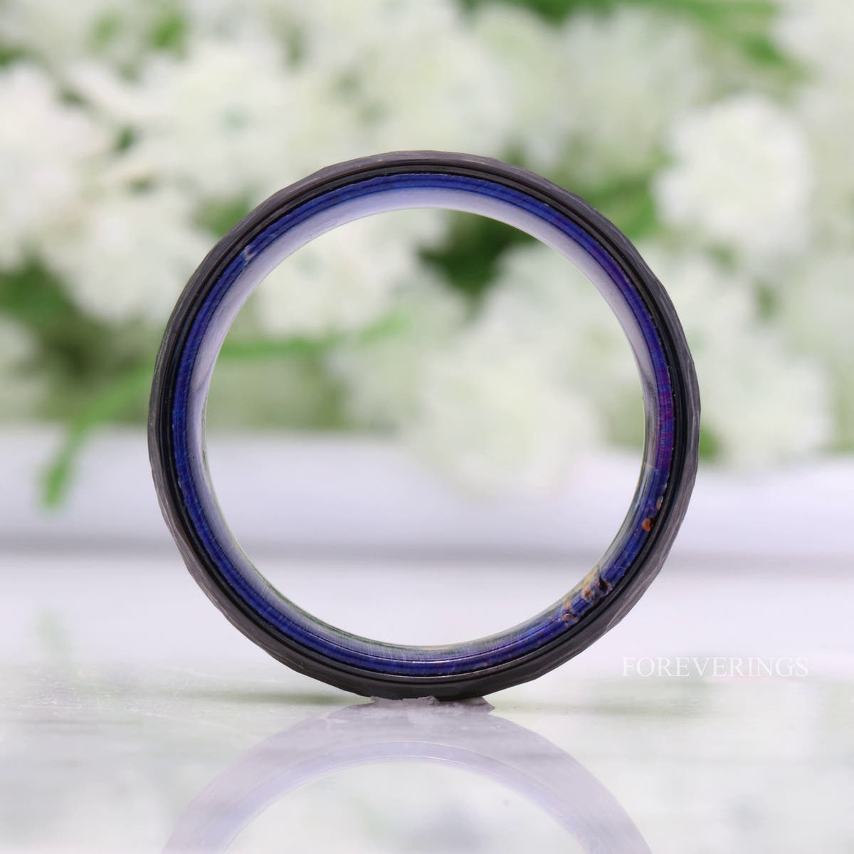 Hammered black tungsten band standing face-on, showing the full blue elder wood lining