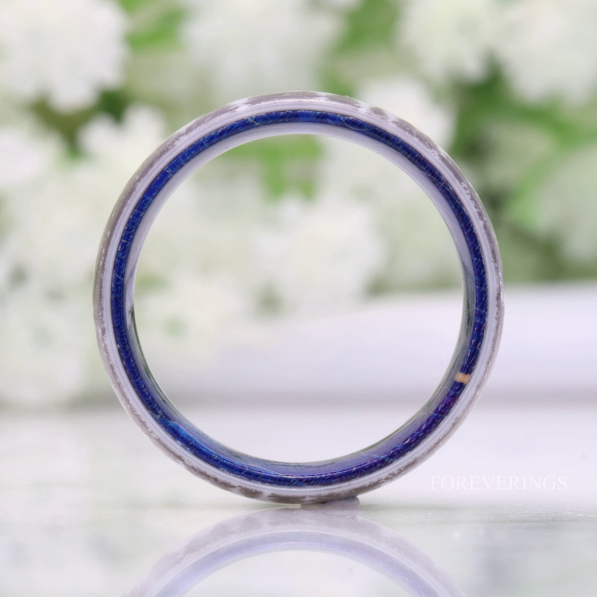 White ceramic forest band standing on edge, viewed straight through to the blue wood lining