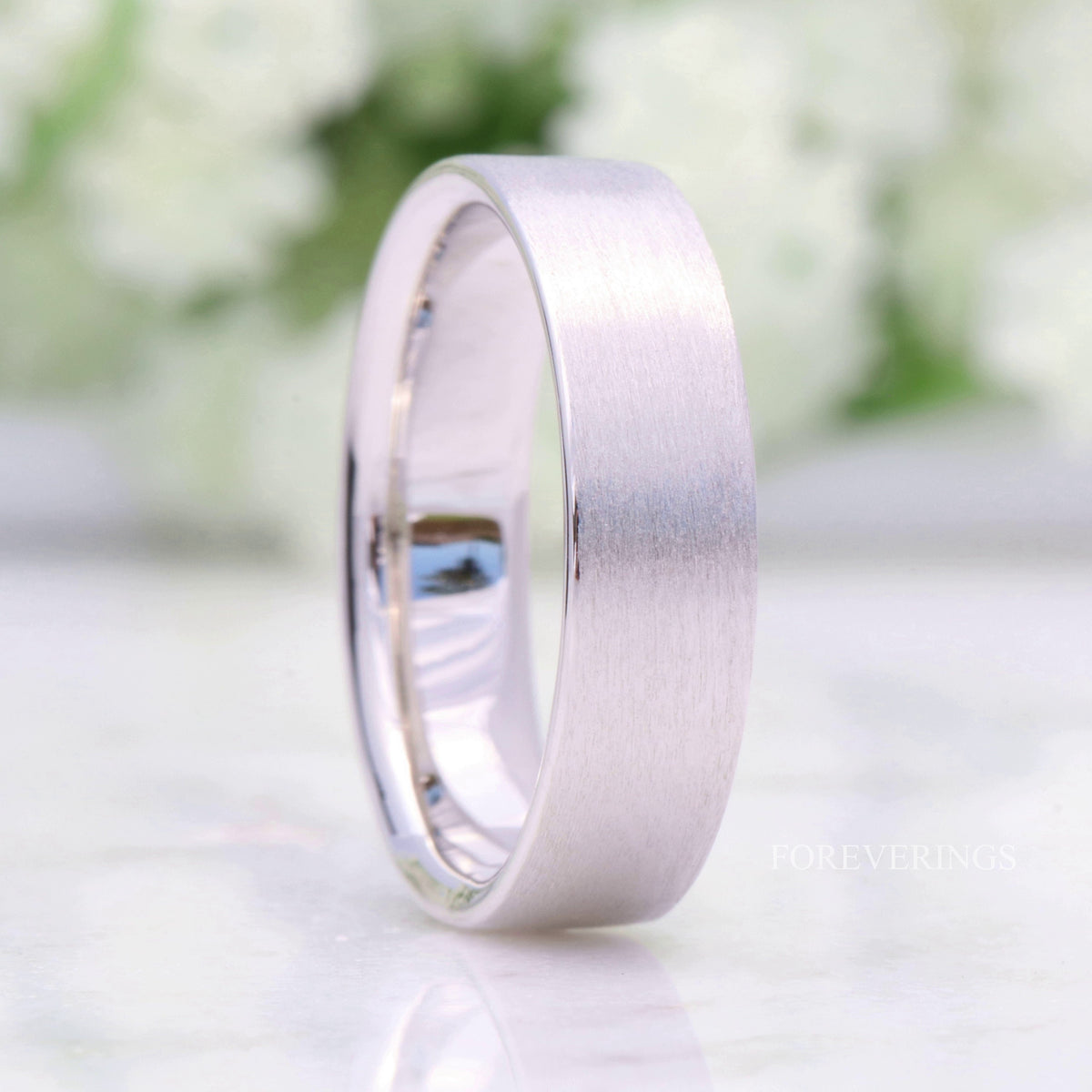 Matte sterling silver wedding band standing on edge, wider view