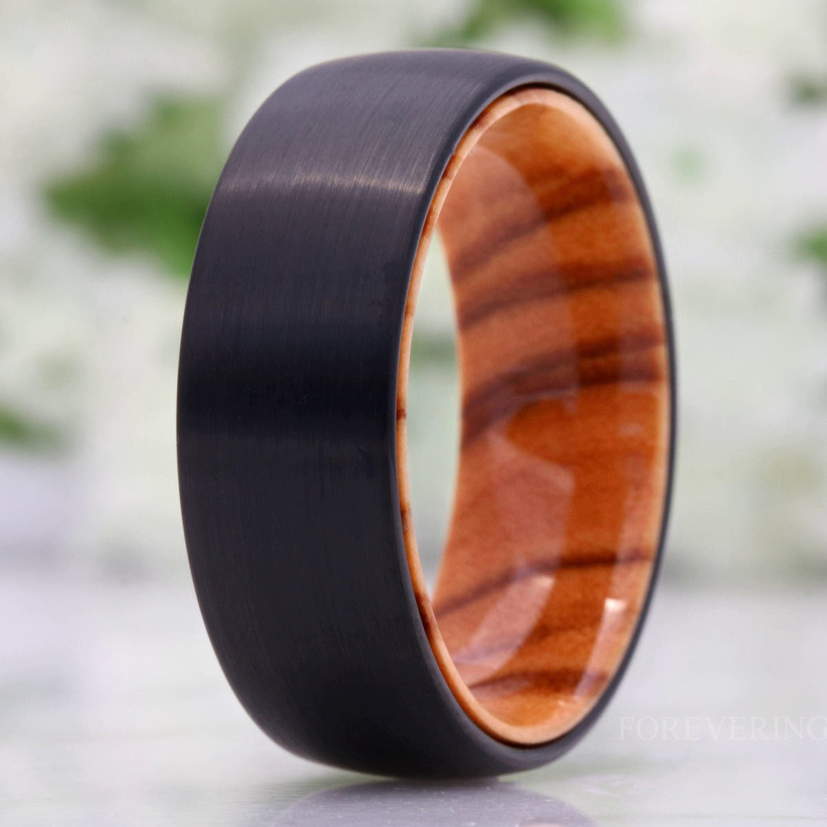 Men's 8mm matte black tungsten band with an olive wood interior, standing on edge