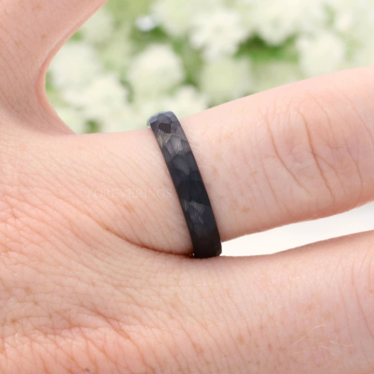 4mm hammered black tungsten band on a finger, close crop
