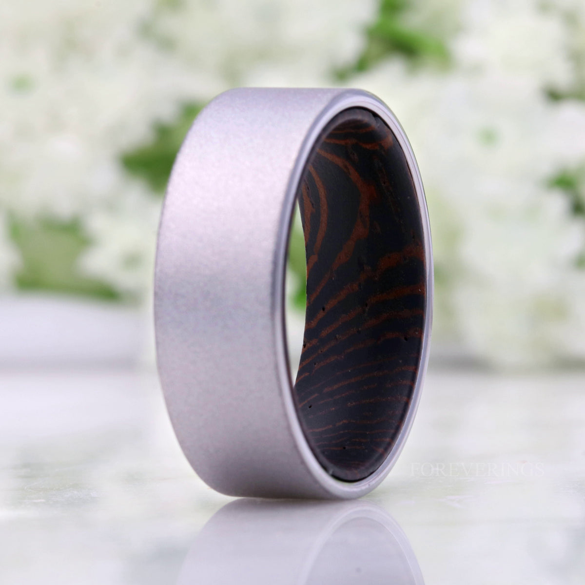 Sandblasted silver tungsten wenge wood band standing upright in a wider view, reflection below