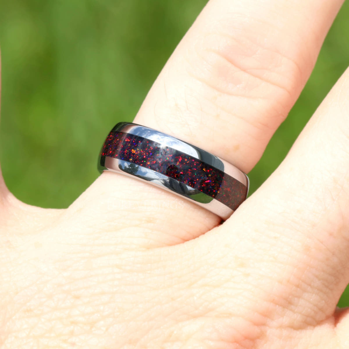 Silver tungsten black fire opal ring worn on a finger, red and purple flashes