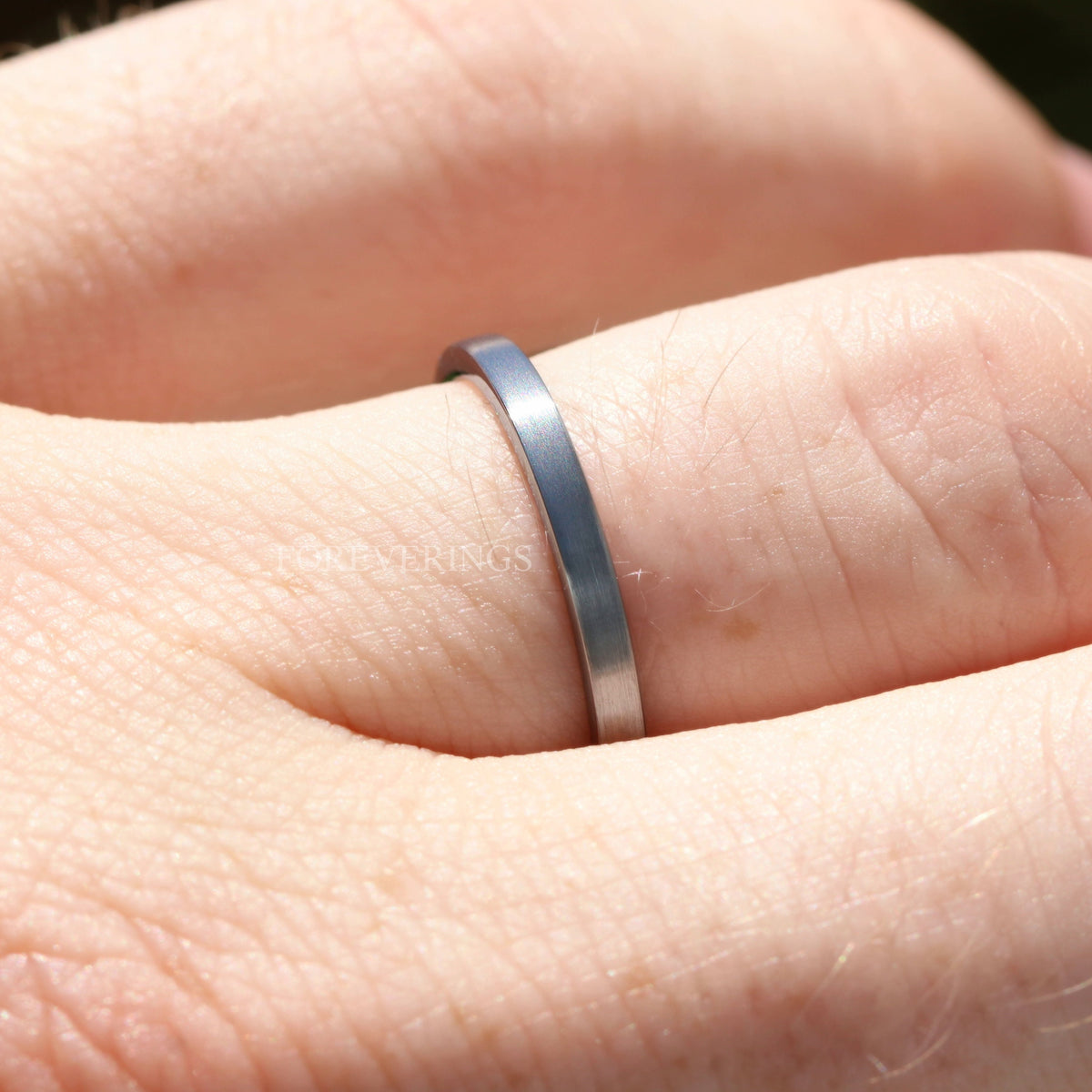 Close-up of the thin 2mm brushed silver tungsten band worn on a finger