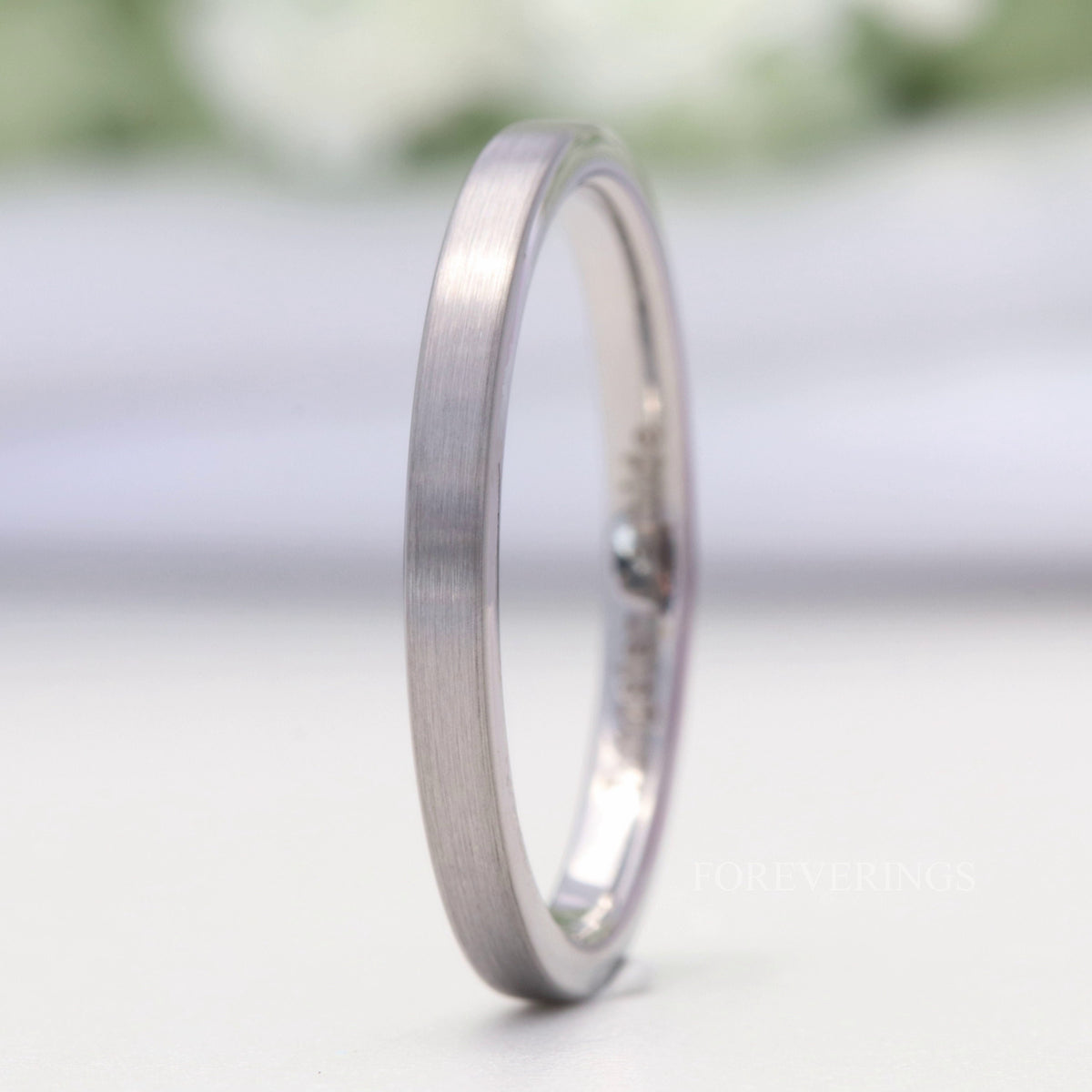 2mm matte silver tungsten band standing on edge, showing its flat profile and polished interior