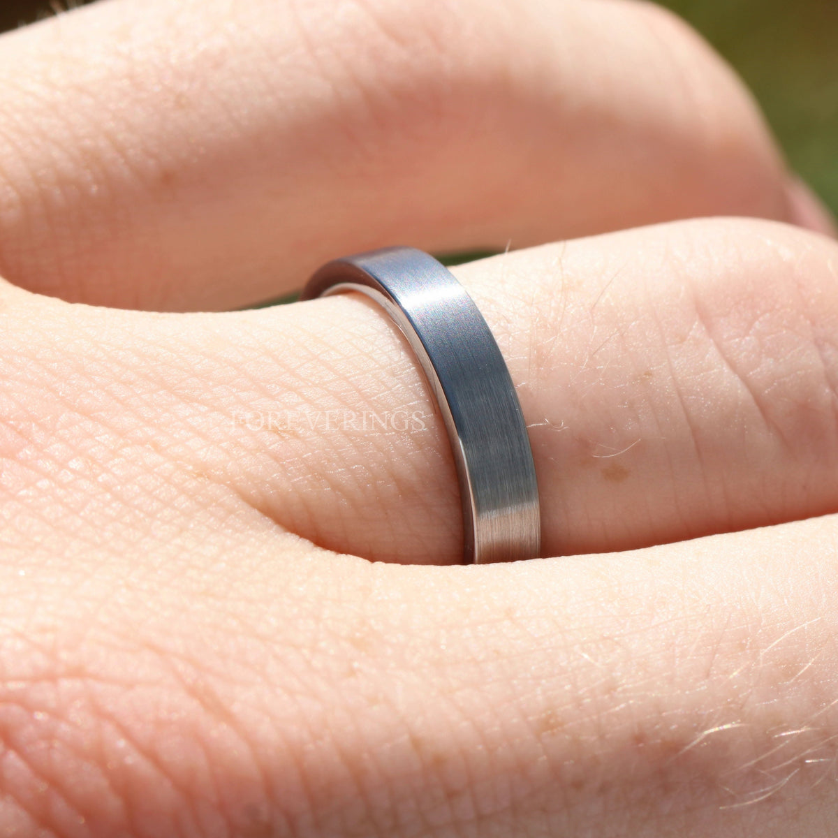 Close-up of the 4mm brushed silver tungsten band on a finger, showing the flat matte surface