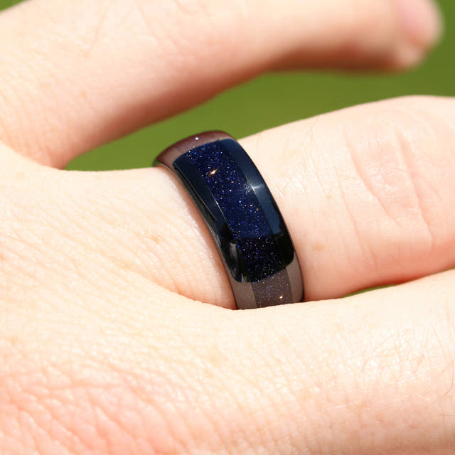 Black tungsten blue sandstone band worn on a finger, close view