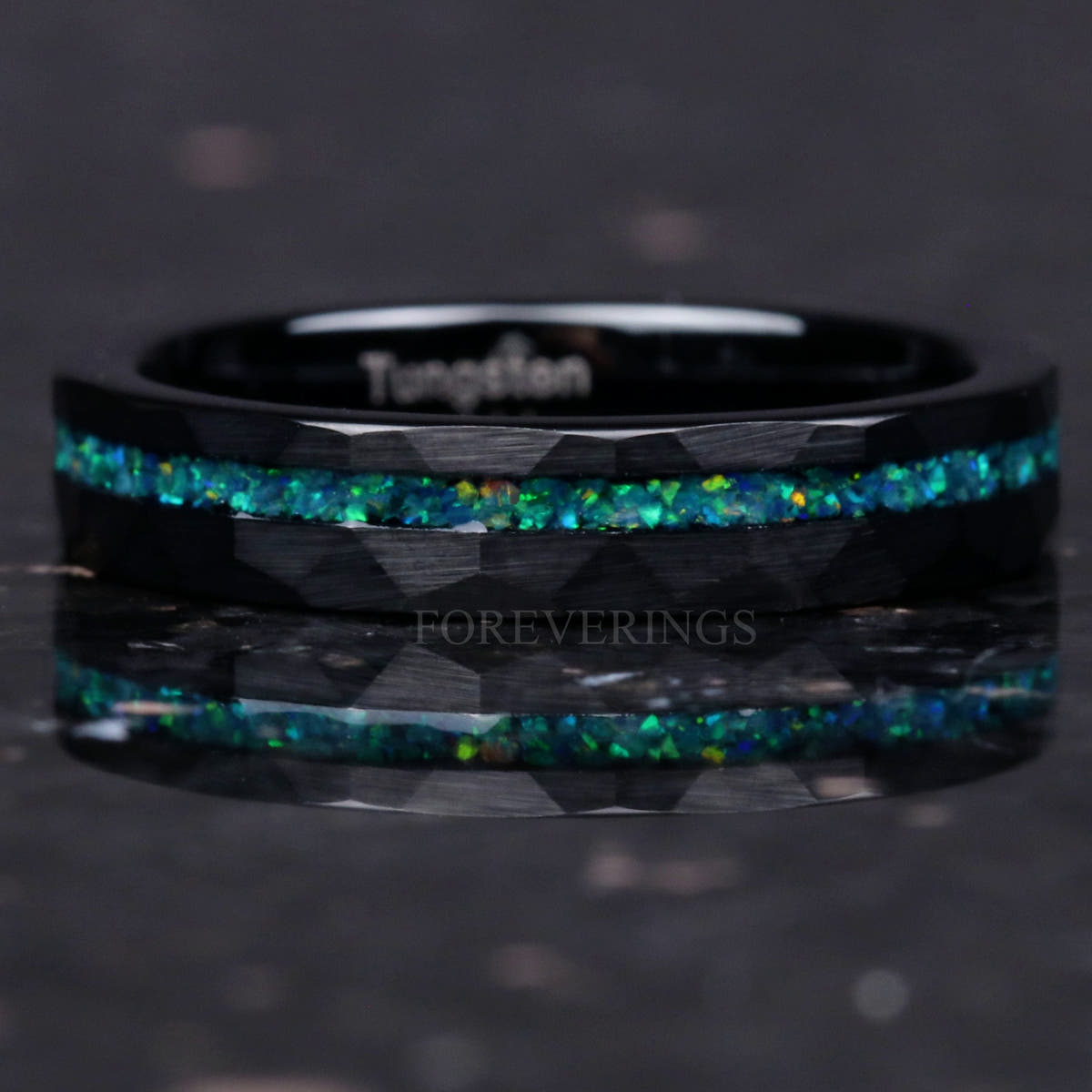 Hammered black tungsten band with an offset green opal stripe lying flat, front view