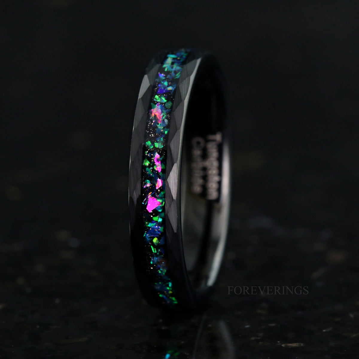 Women's 4mm hammered black tungsten ring with galaxy opal inlay, standing on edge