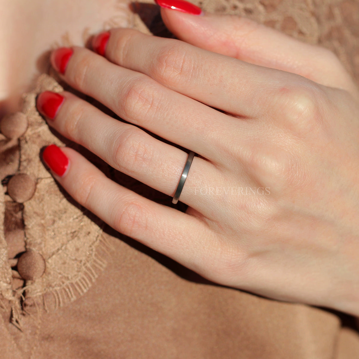 Thin brushed silver tungsten ring worn on a woman's hand, wider view