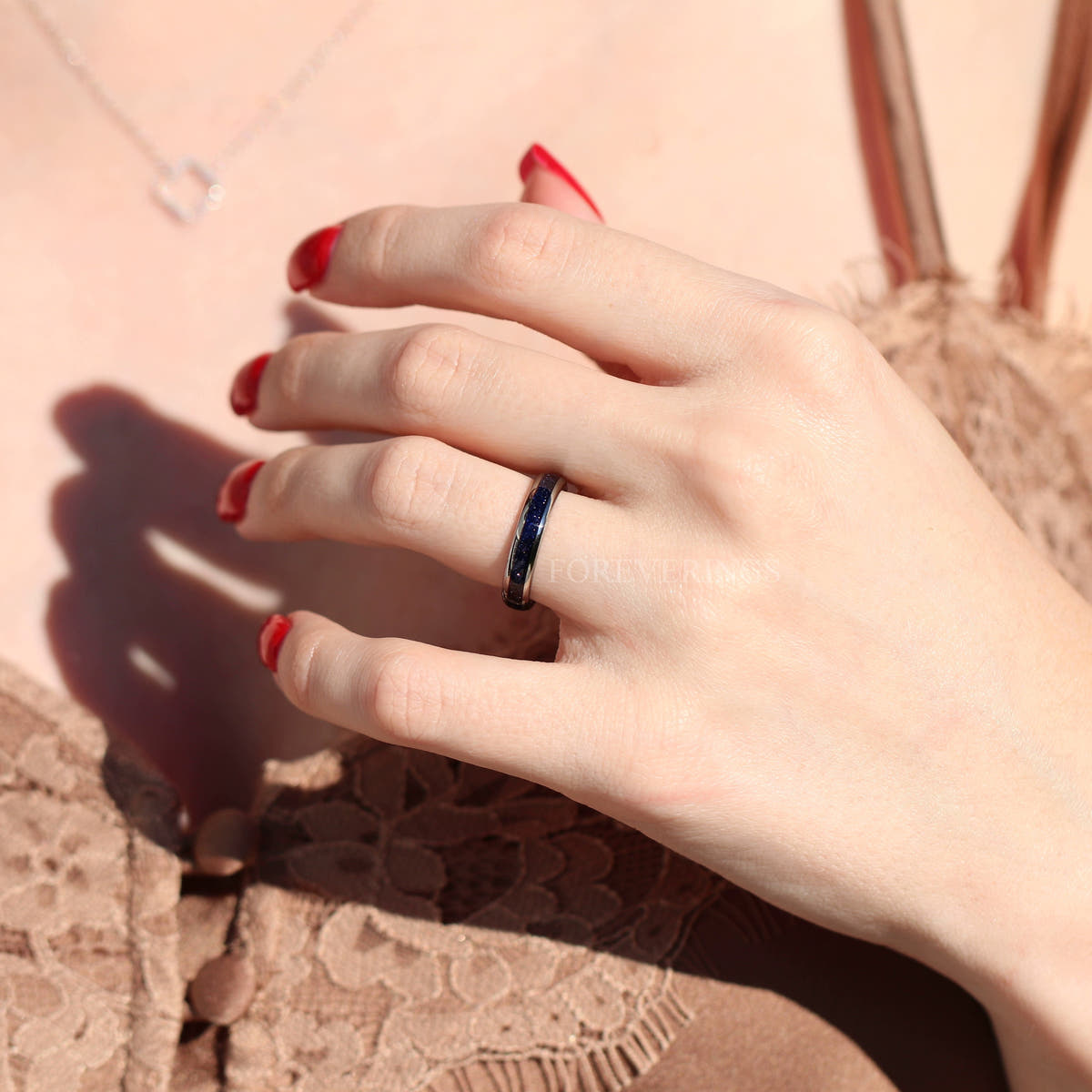 Silver tungsten ring with blue sandstone inlay worn on a hand, wider view