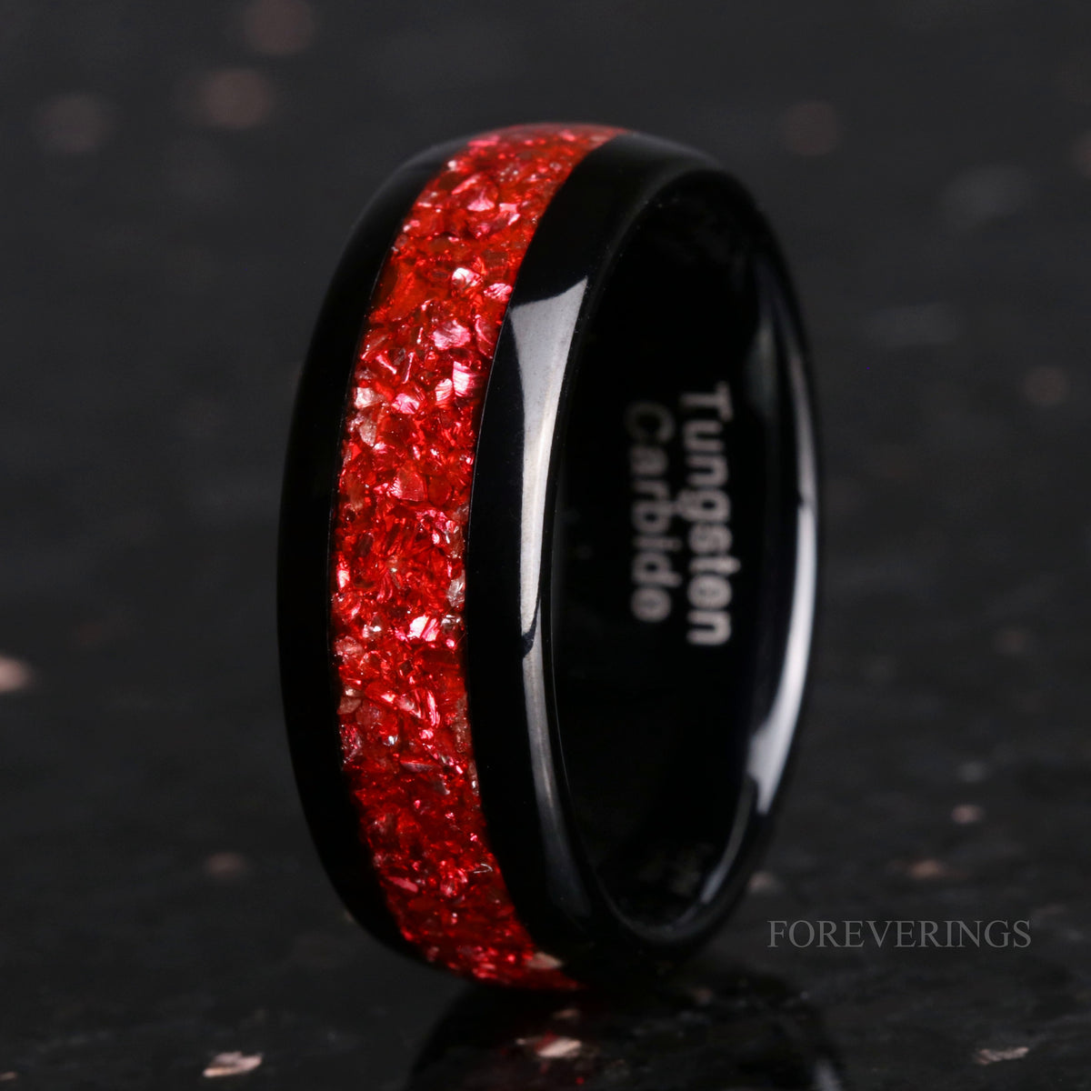 Men's 8mm black tungsten band with crushed ruby inlay, standing at an angle