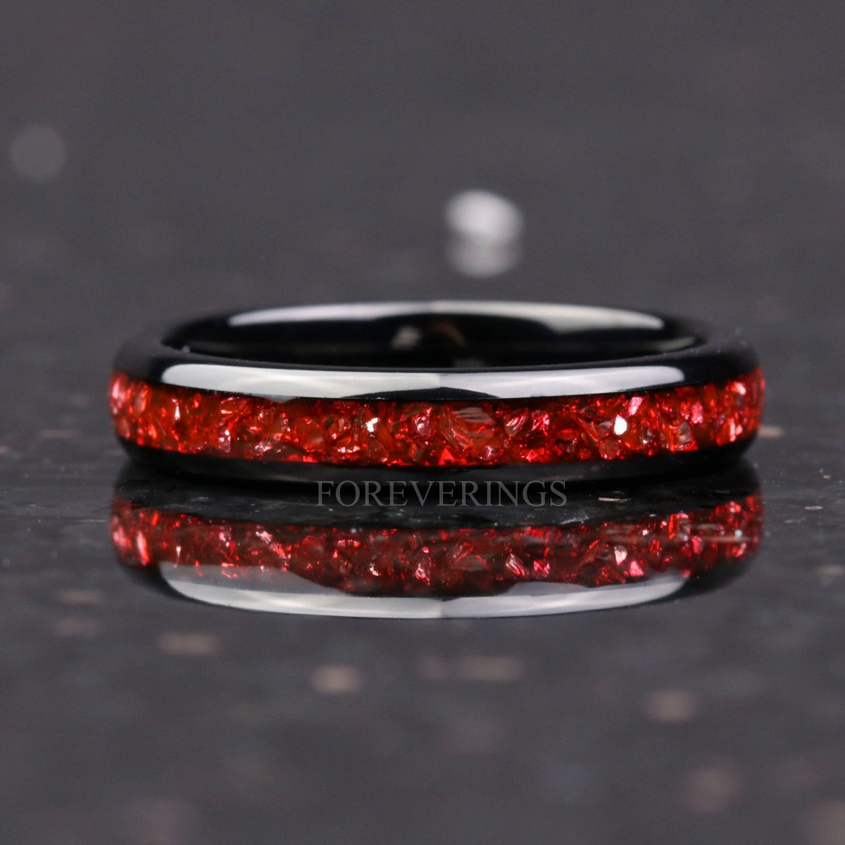 Black tungsten band shown straight on, crushed ruby across the polished dome
