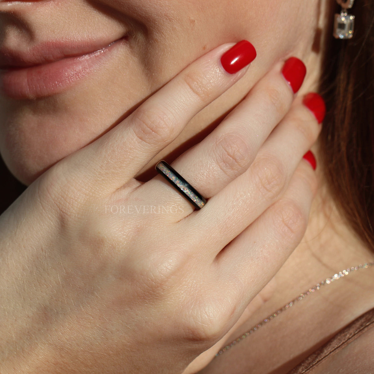 Black tungsten white fire opal ring worn on a woman's hand