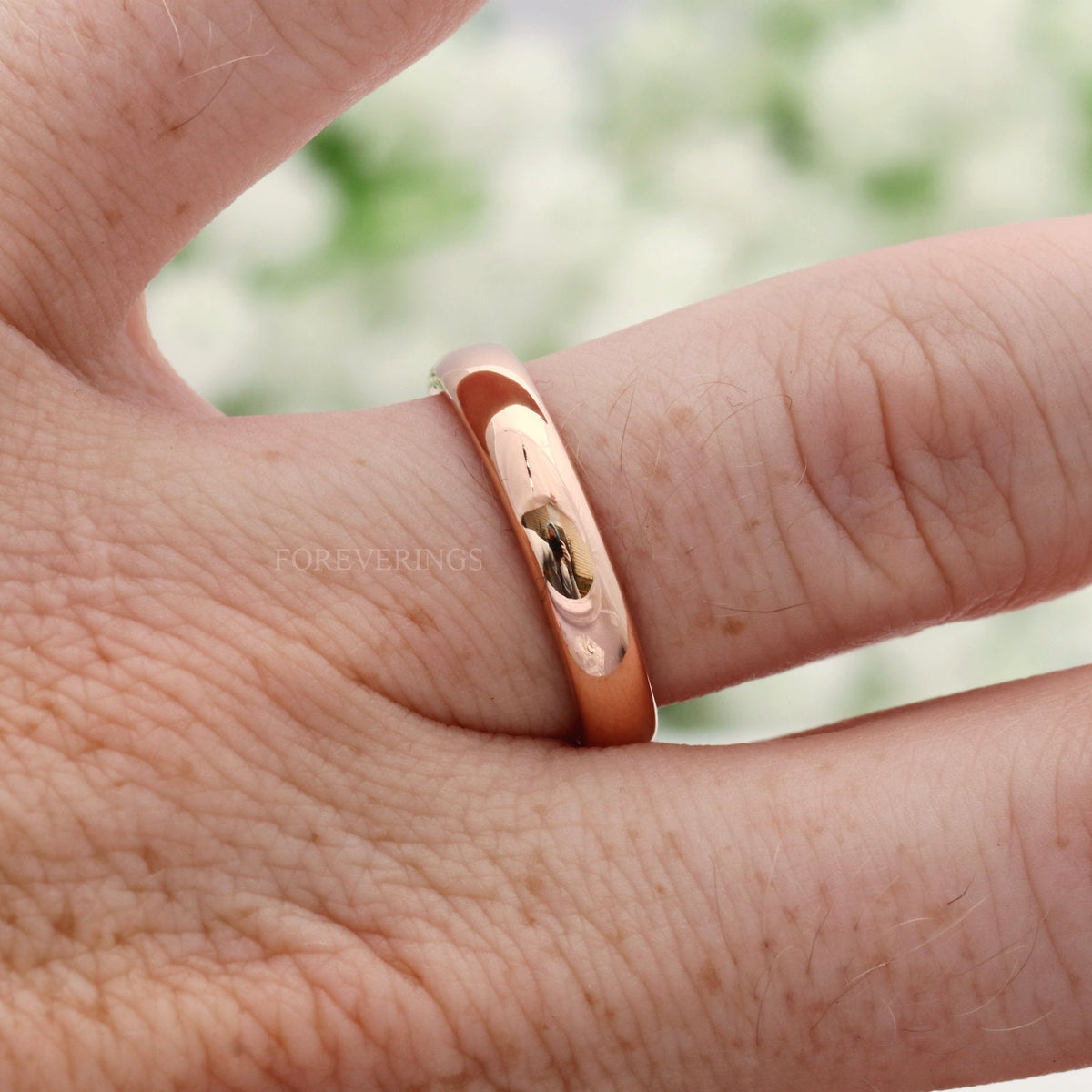 4mm rose gold tungsten band worn on a finger, close crop
