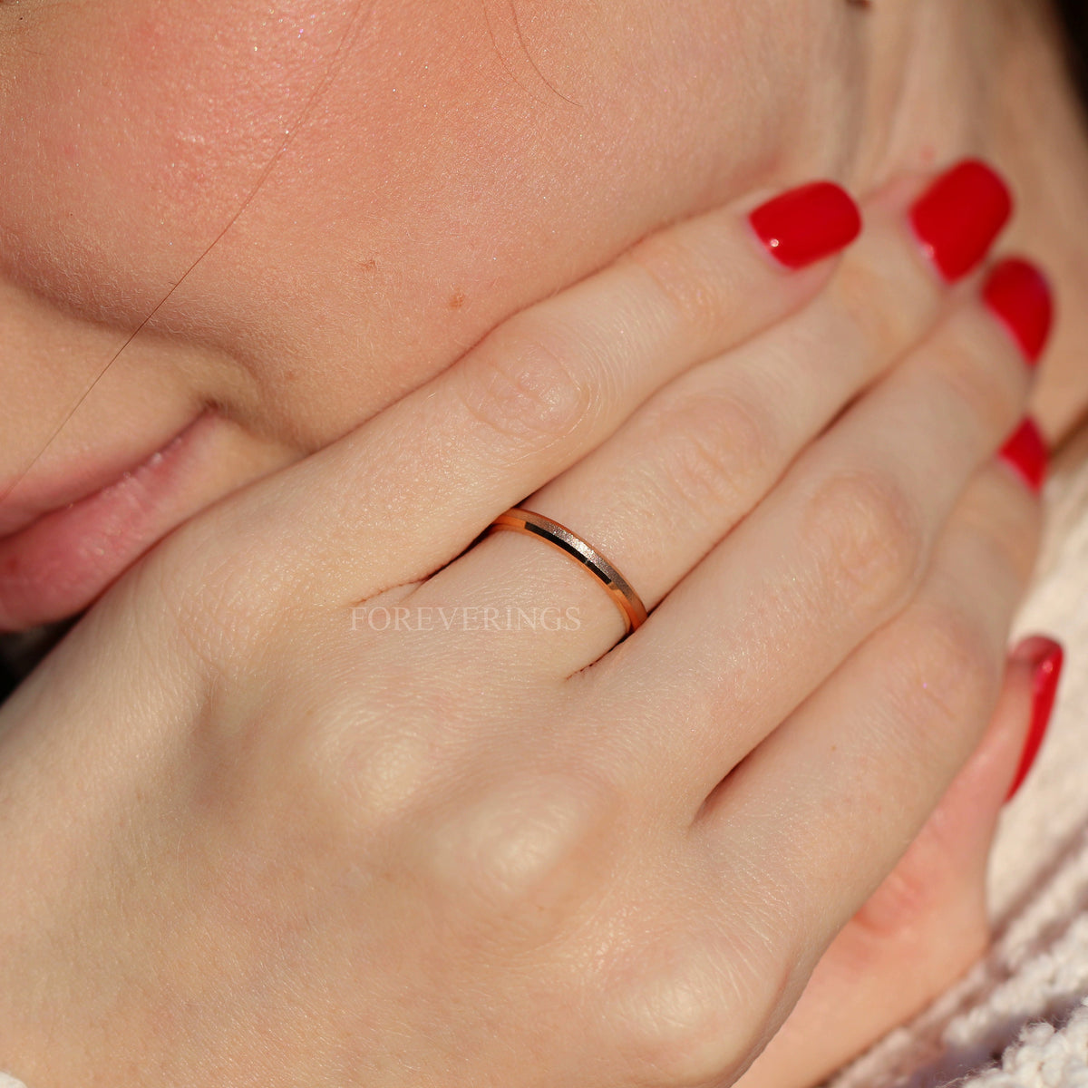 Narrow sandblasted rose gold band worn on a woman's hand