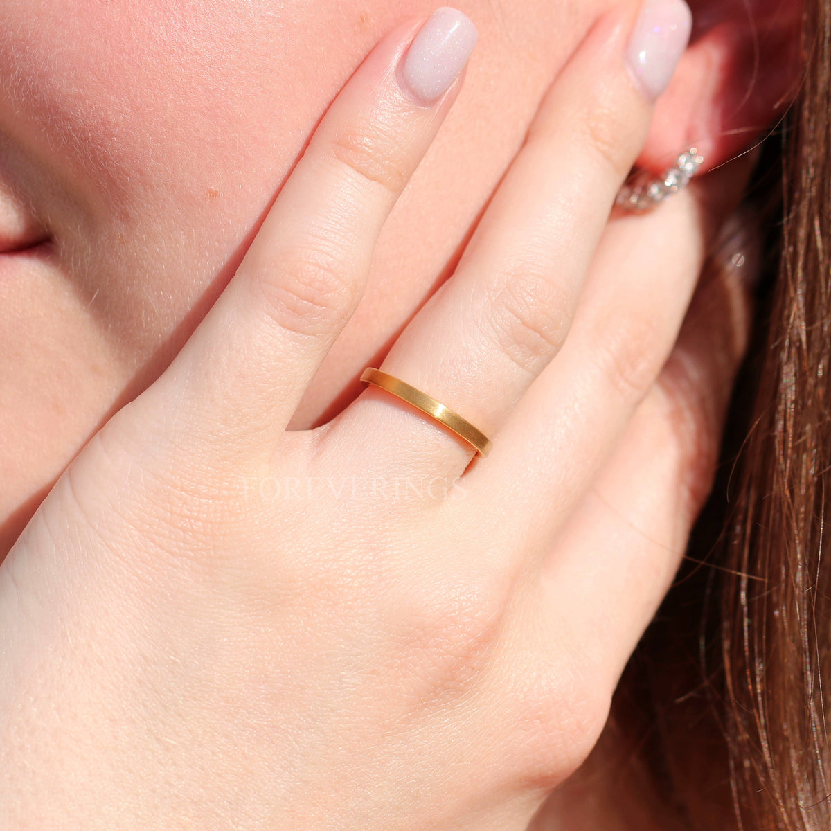 Women's 2mm matte gold tungsten band worn on a hand