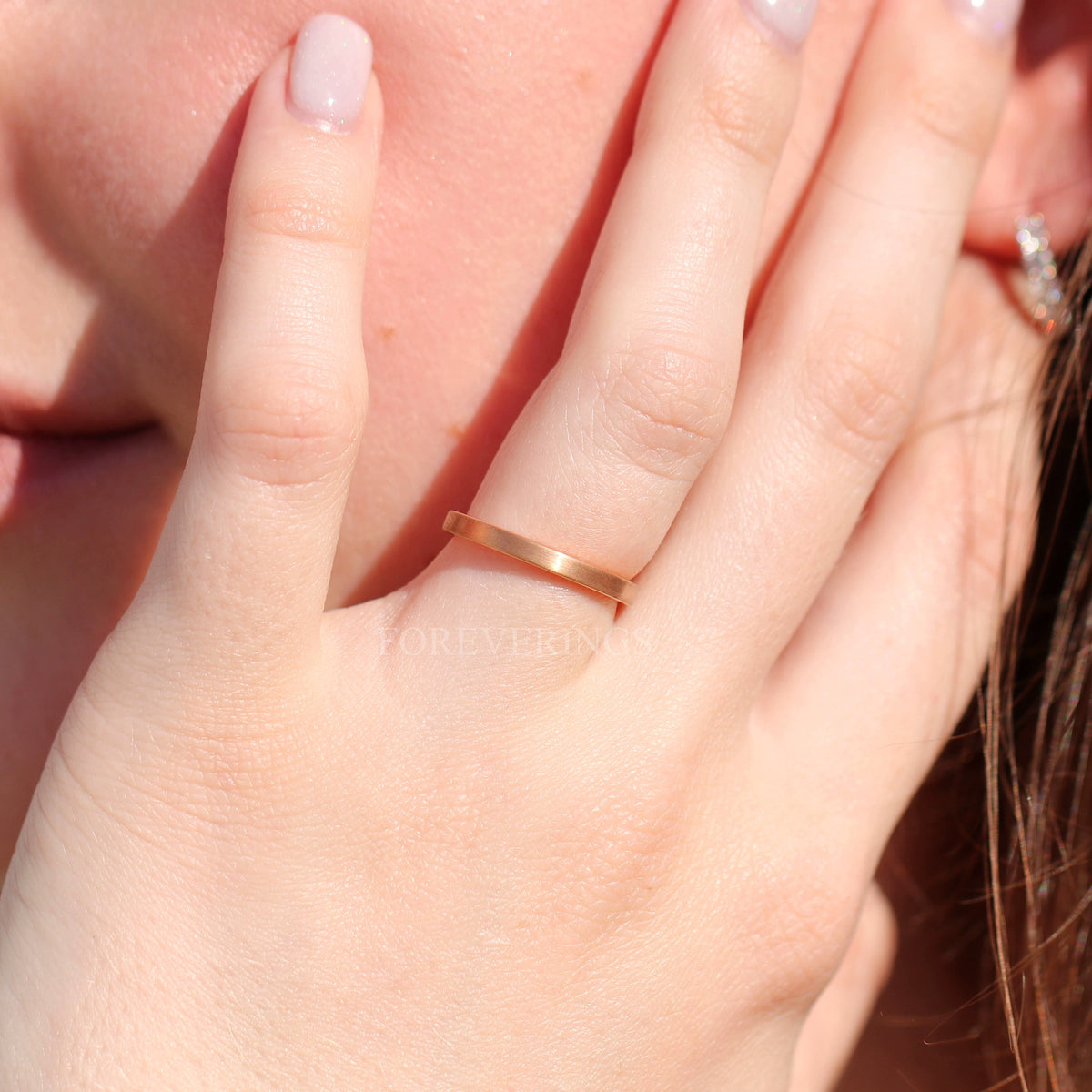 Thin matte rose gold tungsten band worn on a woman's hand