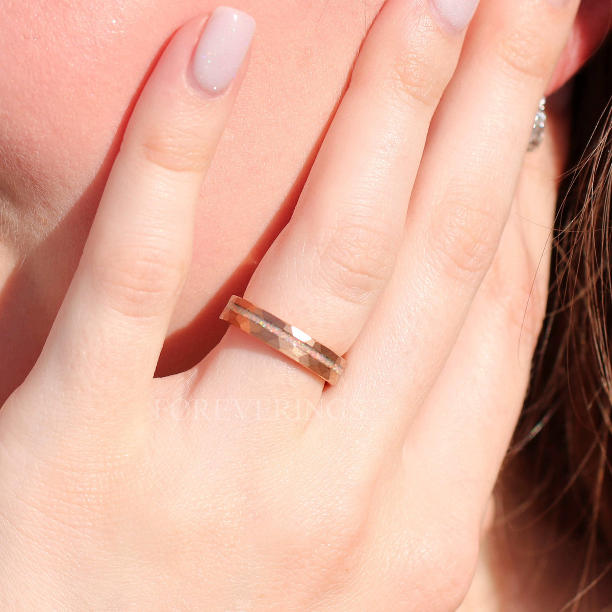 Women's 4mm hammered rose gold tungsten ring worn on a hand