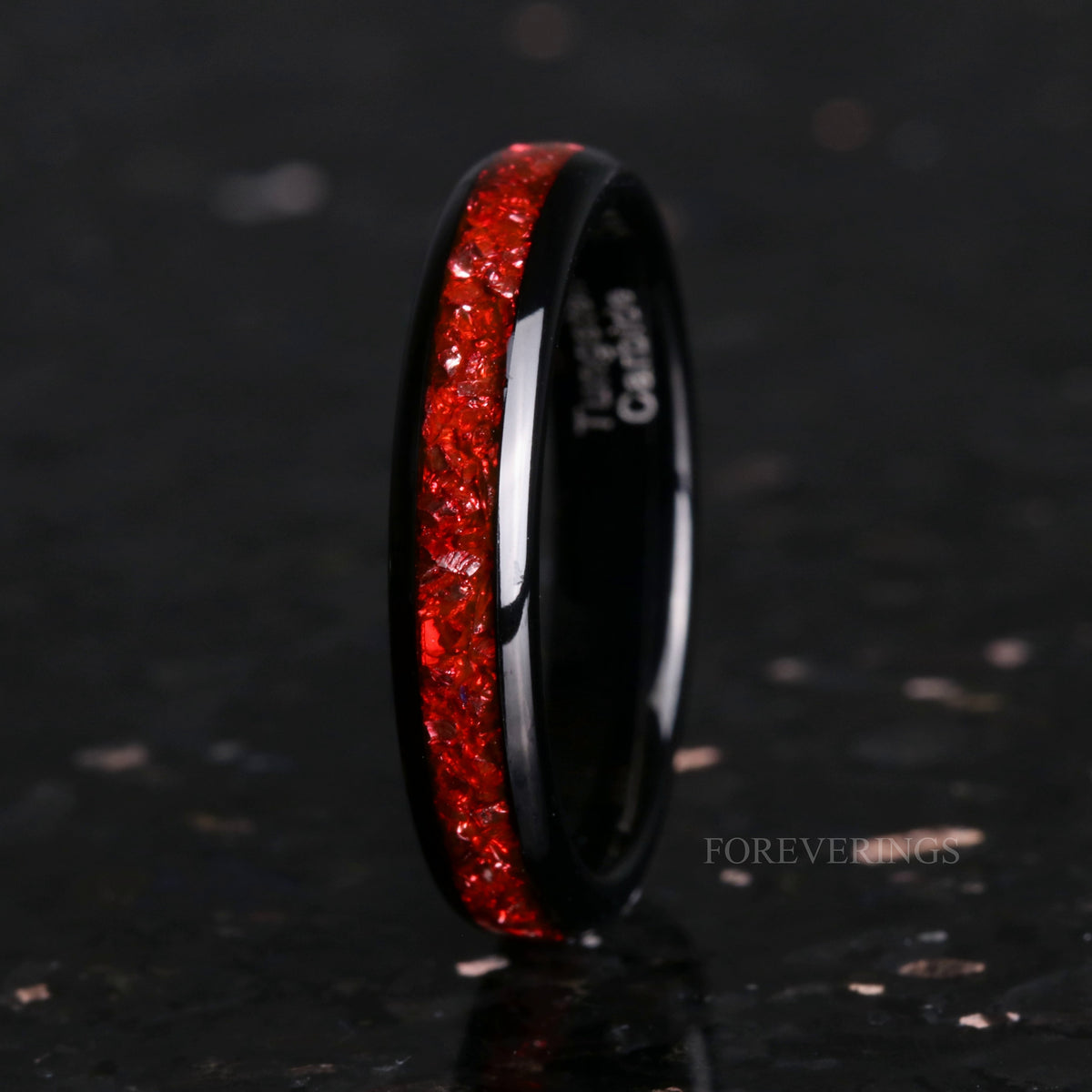 4mm black tungsten band with ruby inlay standing on edge in a wider view