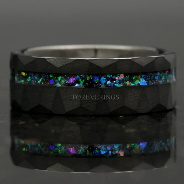 Hammered black tungsten galaxy opal ring lying flat, front view with reflection