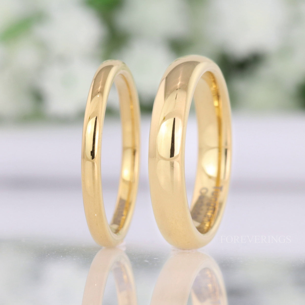 Men's and women's 2mm and 4mm gold tungsten rings standing side by side to compare widths