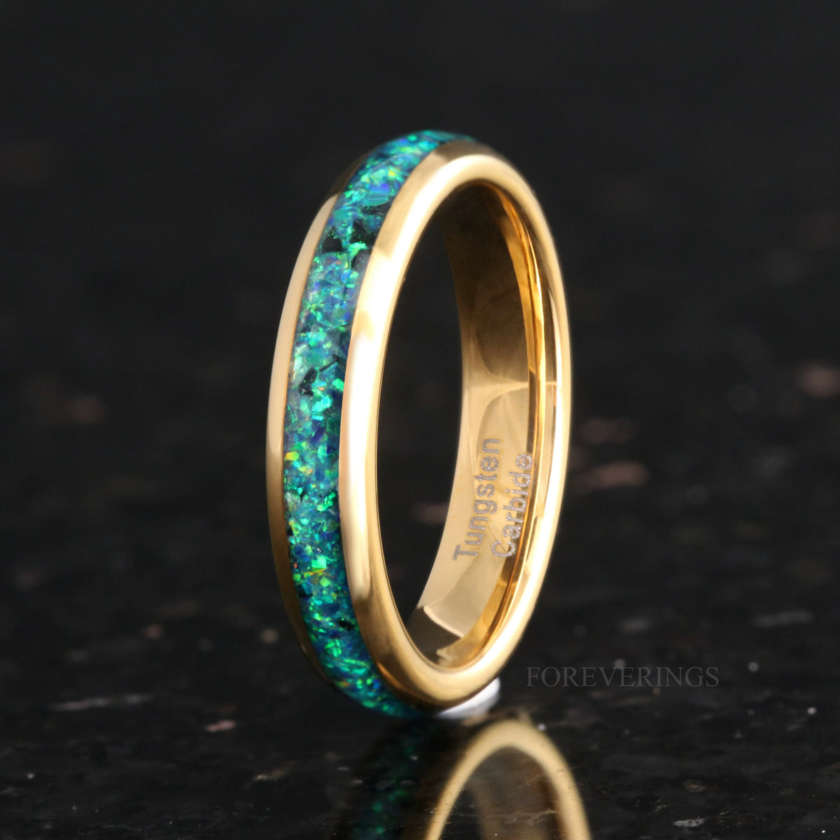 Women's 4mm gold tungsten ring with emerald fire opal inlay, standing on edge