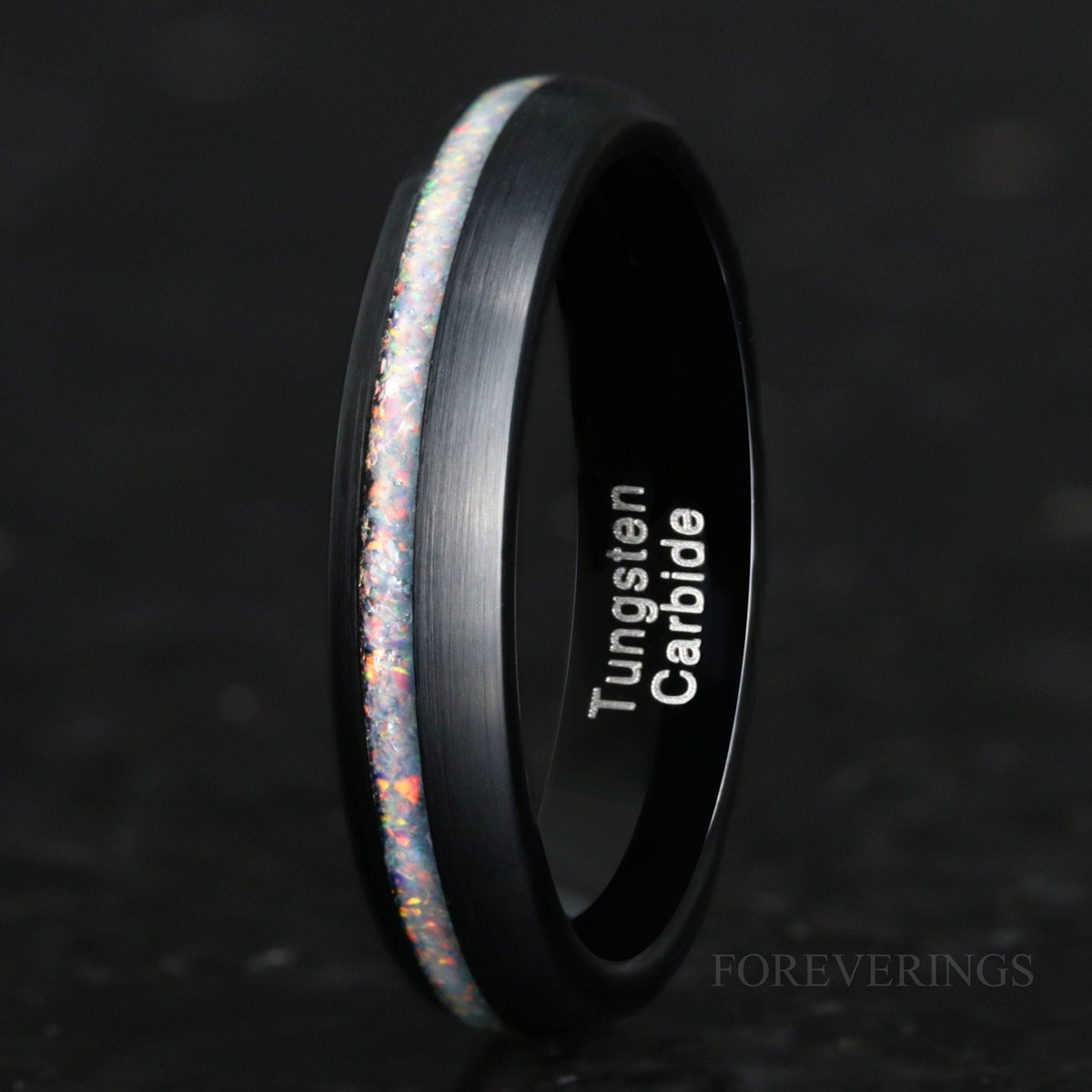 4mm brushed black tungsten ring with a white fire opal stripe, standing at an angle