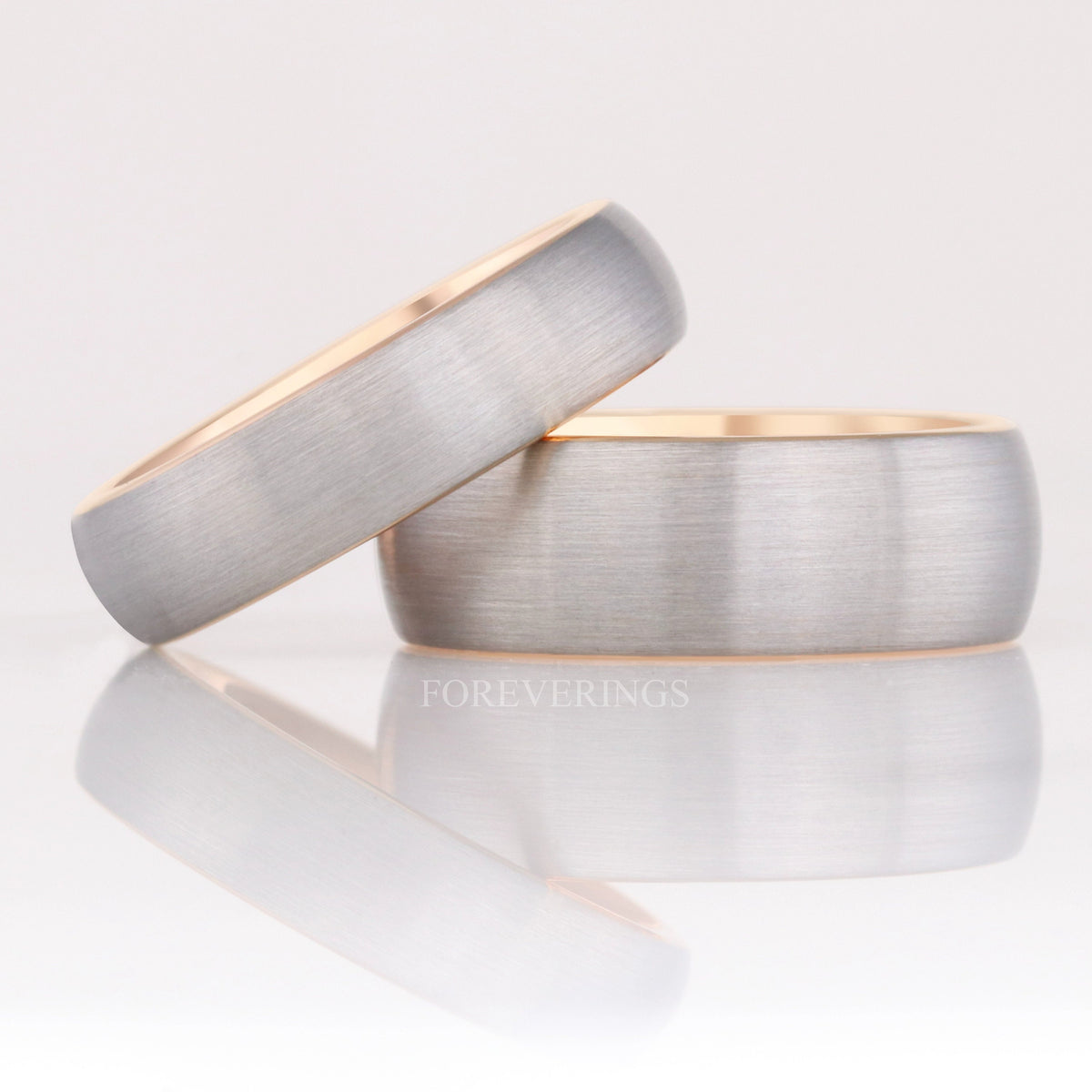Two widths of the silver and rose gold tungsten band, the narrower leaning on the wider