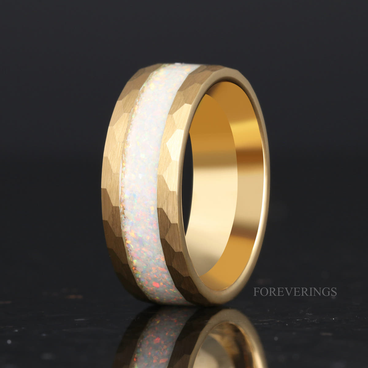 Men's 8mm hammered gold tungsten ring with crushed white fire opal inlay, standing at an angle