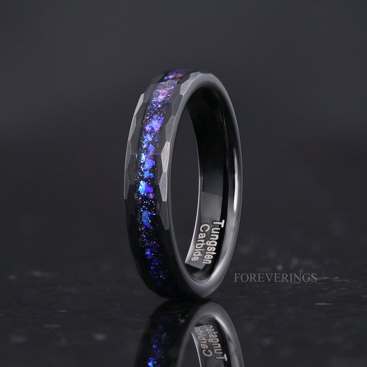 Women's 4mm hammered black tungsten ring with blue nebula inlay, standing with reflection