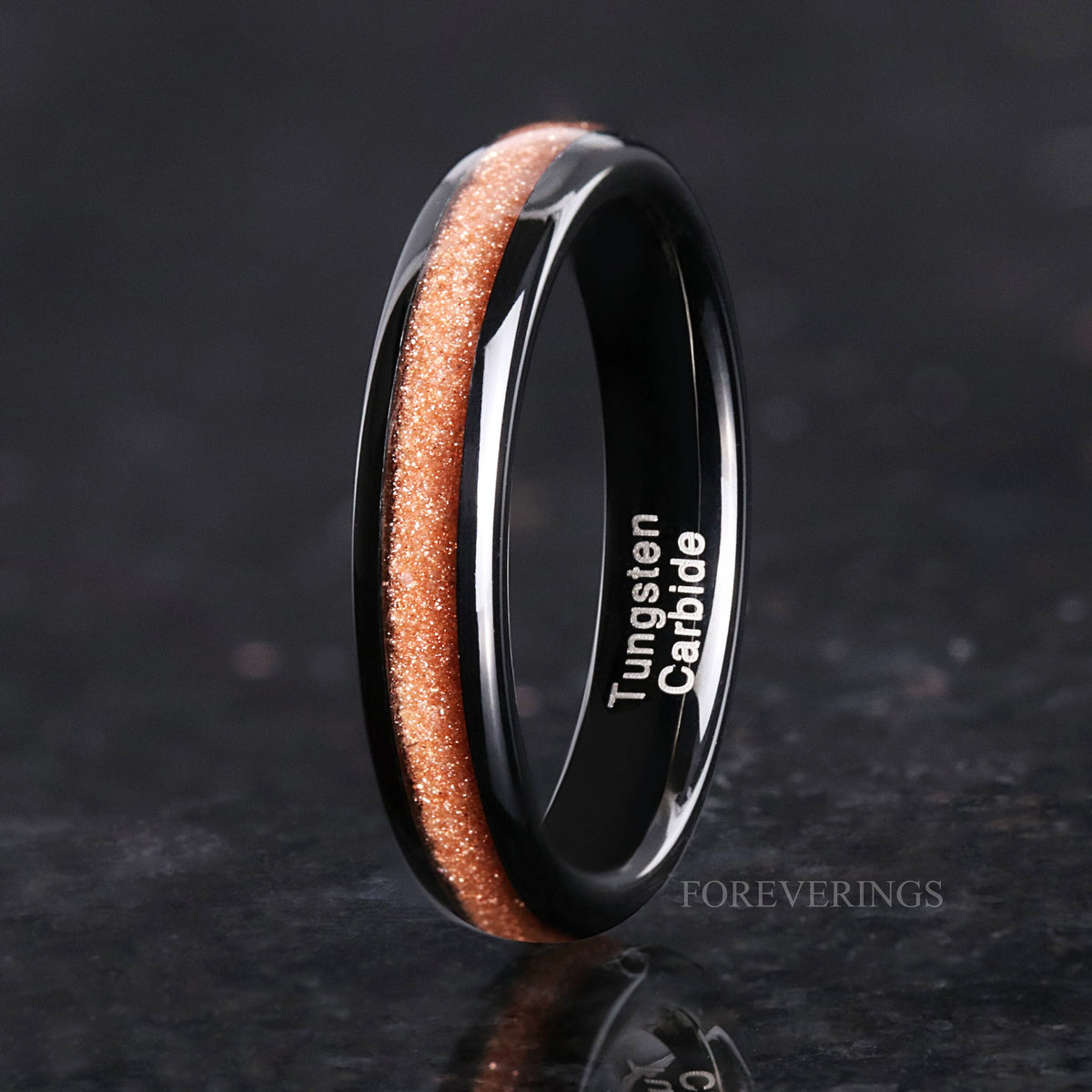 Women's 4mm black tungsten ring with crushed red sandstone inlay, standing on edge