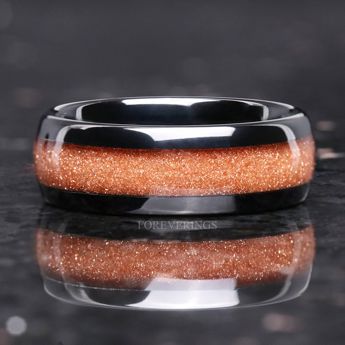 8mm black tungsten band with crushed red sandstone inlay lying flat, straight on with reflection