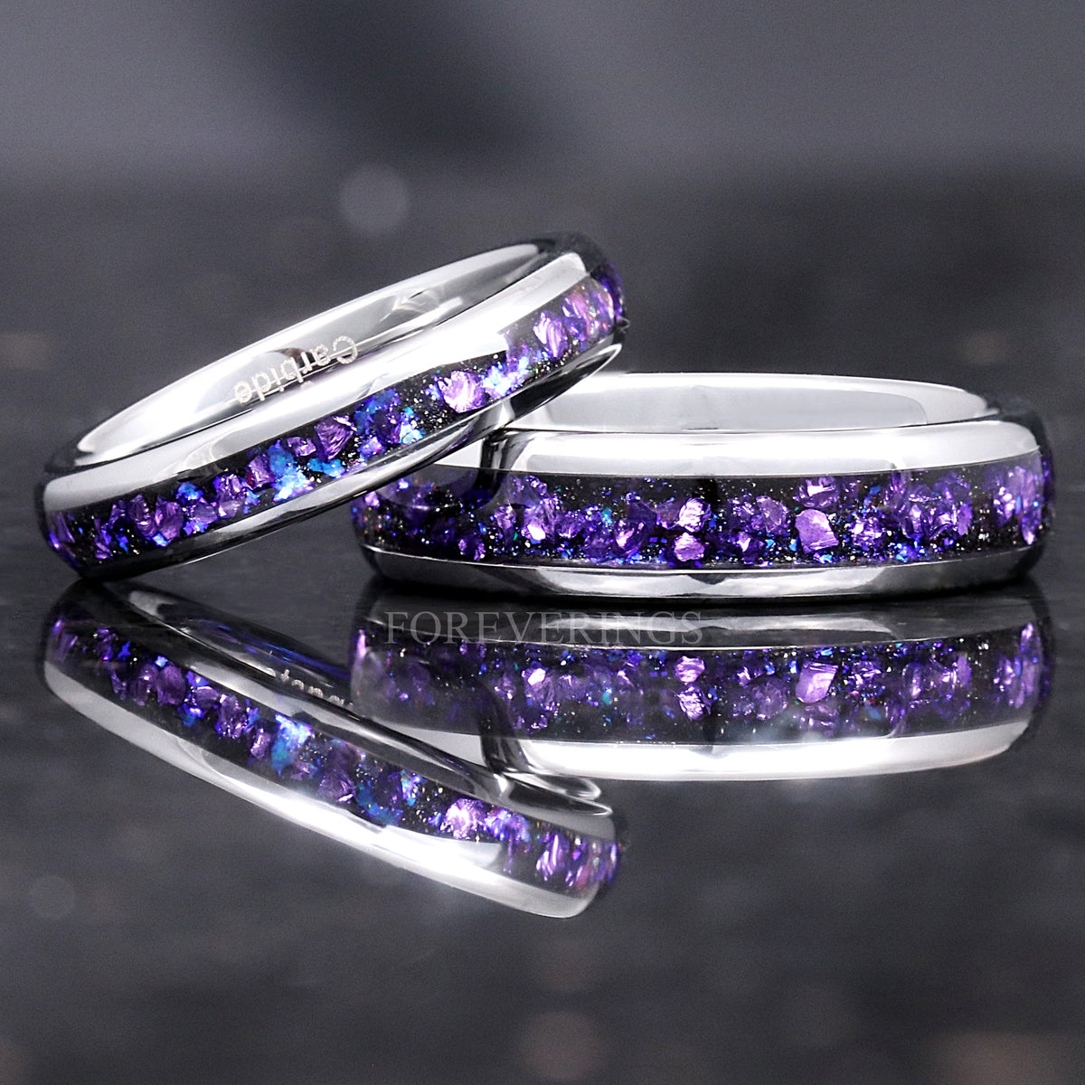 Narrow silver tungsten band resting on a wider one, purple sandstone inlay, close crop