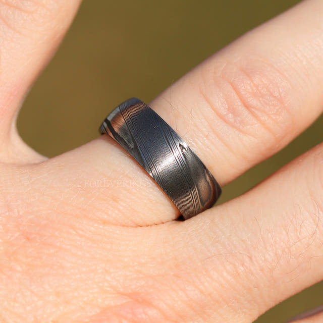 8mm two-tone Damascus steel band with a wavy grain pattern, worn on a finger