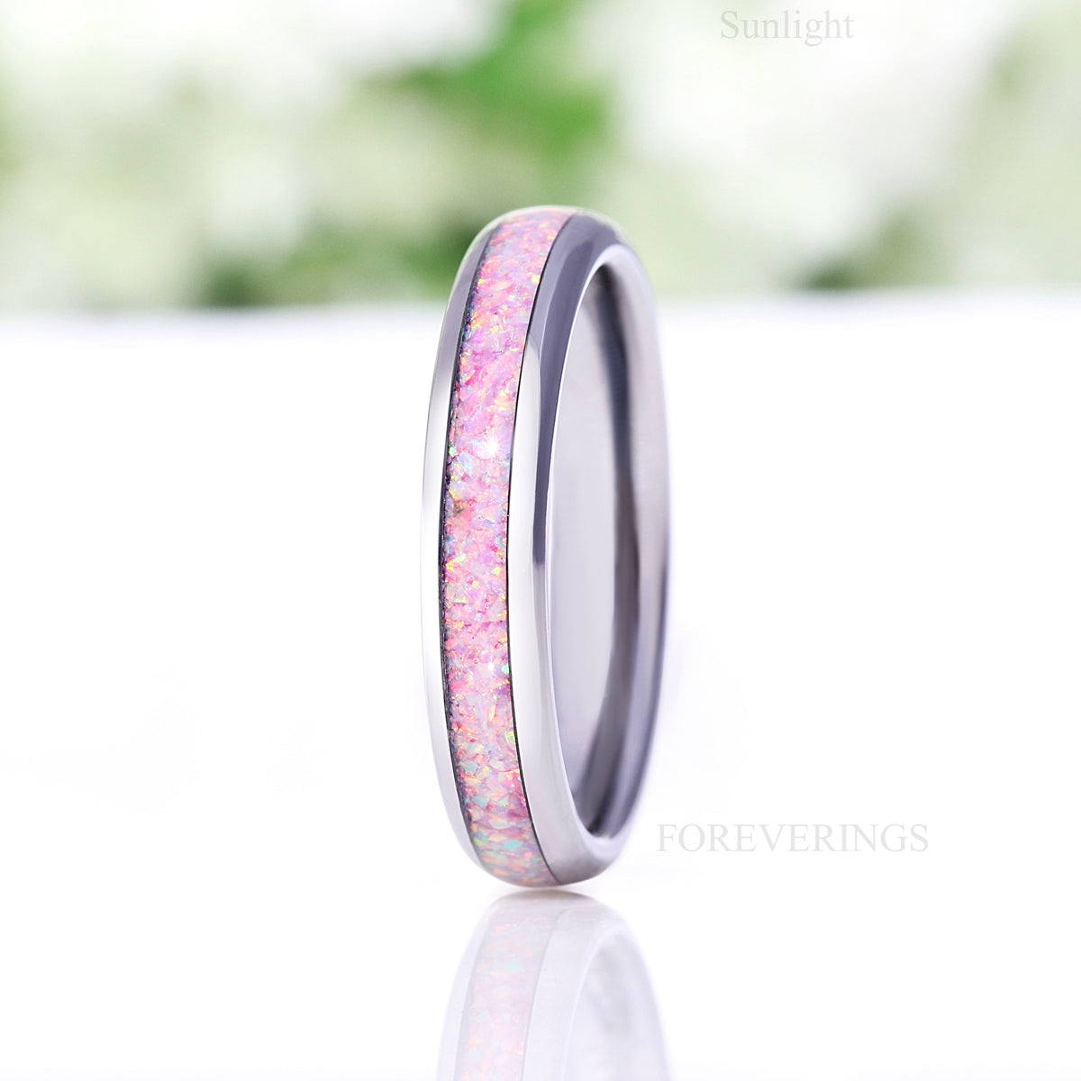 Silver tungsten unicorn fire opal ring standing on edge in sunlight, side view