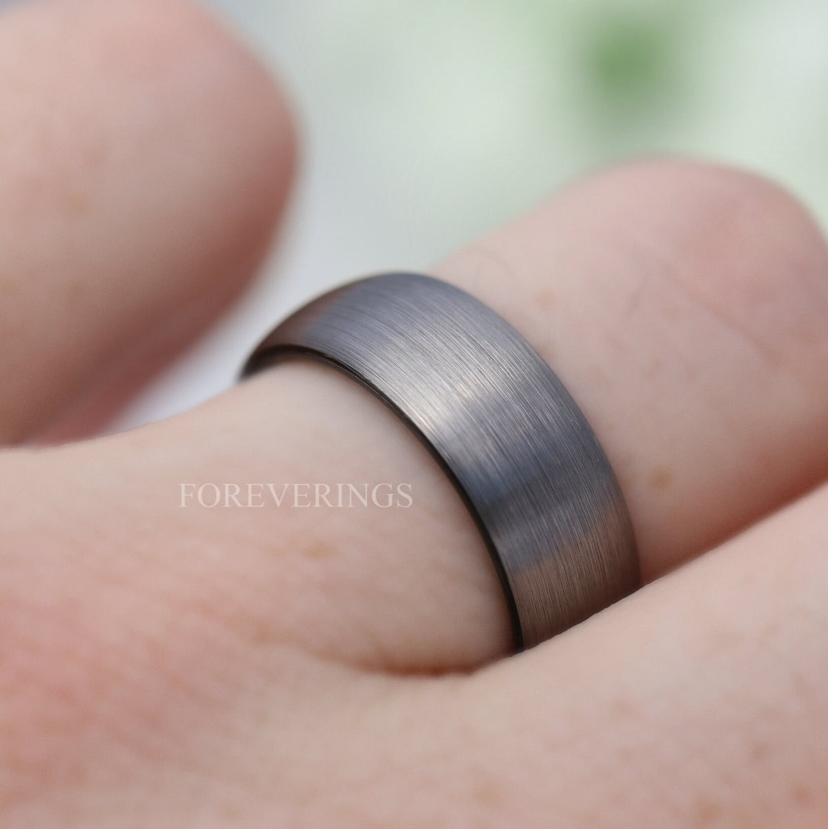 Men's brushed silver tungsten band with black interior worn on a finger
