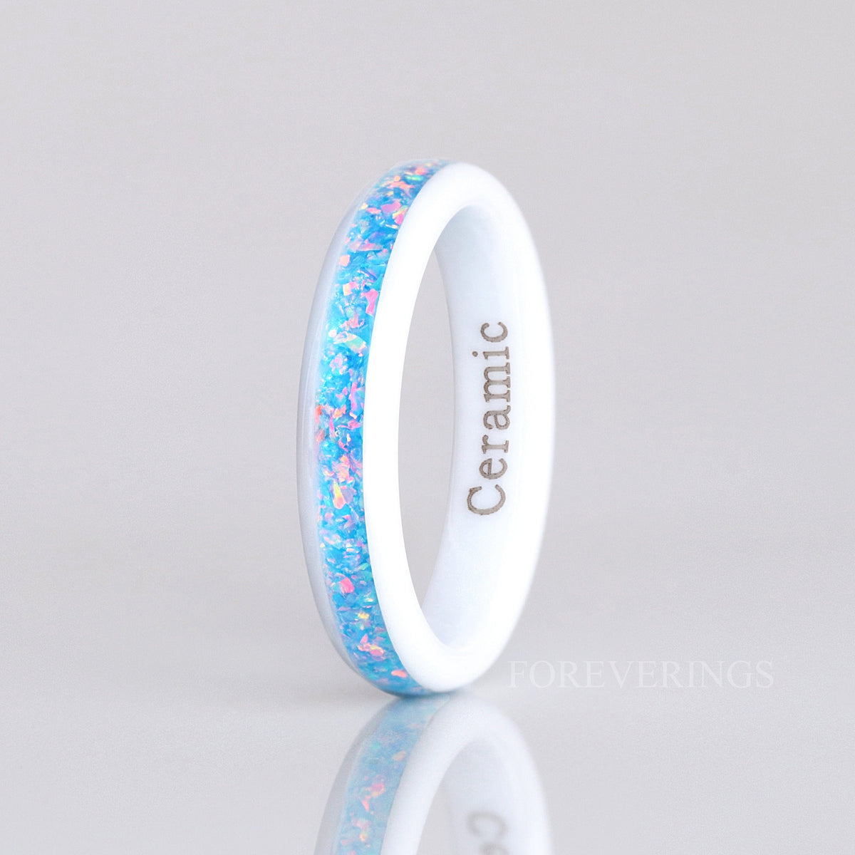 4mm white ceramic rainbow opal ring standing on edge in a wider view