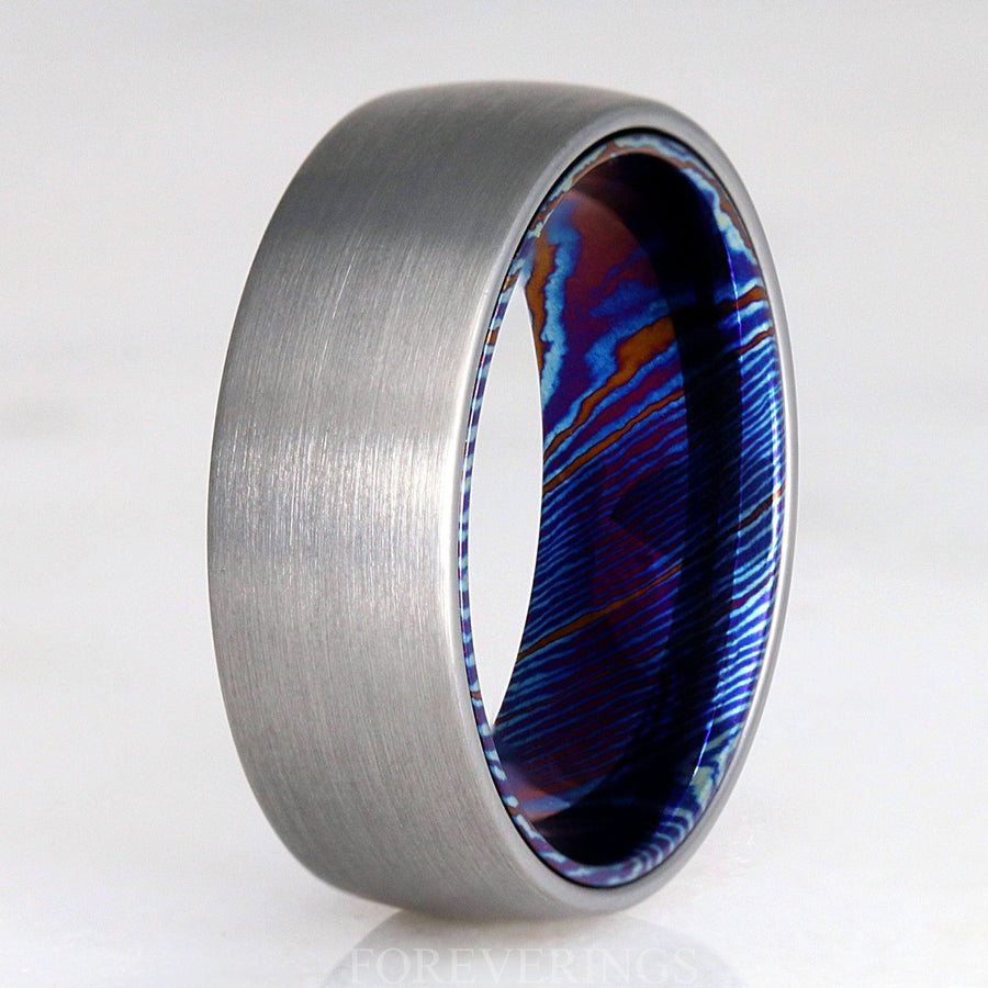 Men's 8mm matte silver tungsten dome band with a blue Timascus inner sleeve, angled view